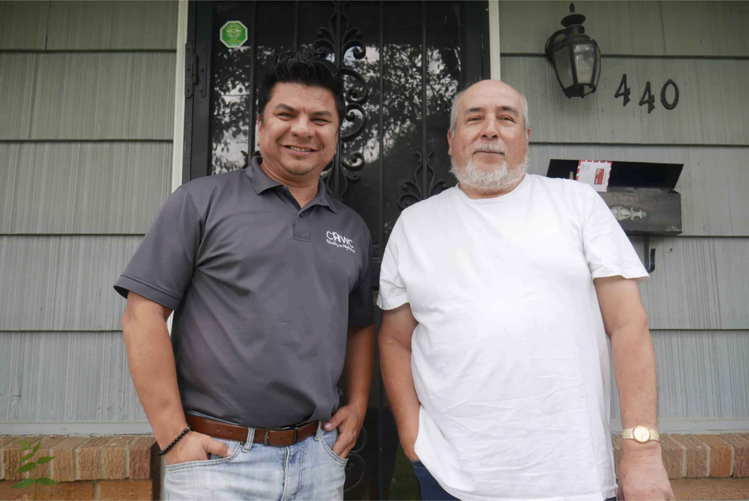 Lisandro, CHWC's housing counselor, and David, a KCK homeowner, stand on David's front porch.