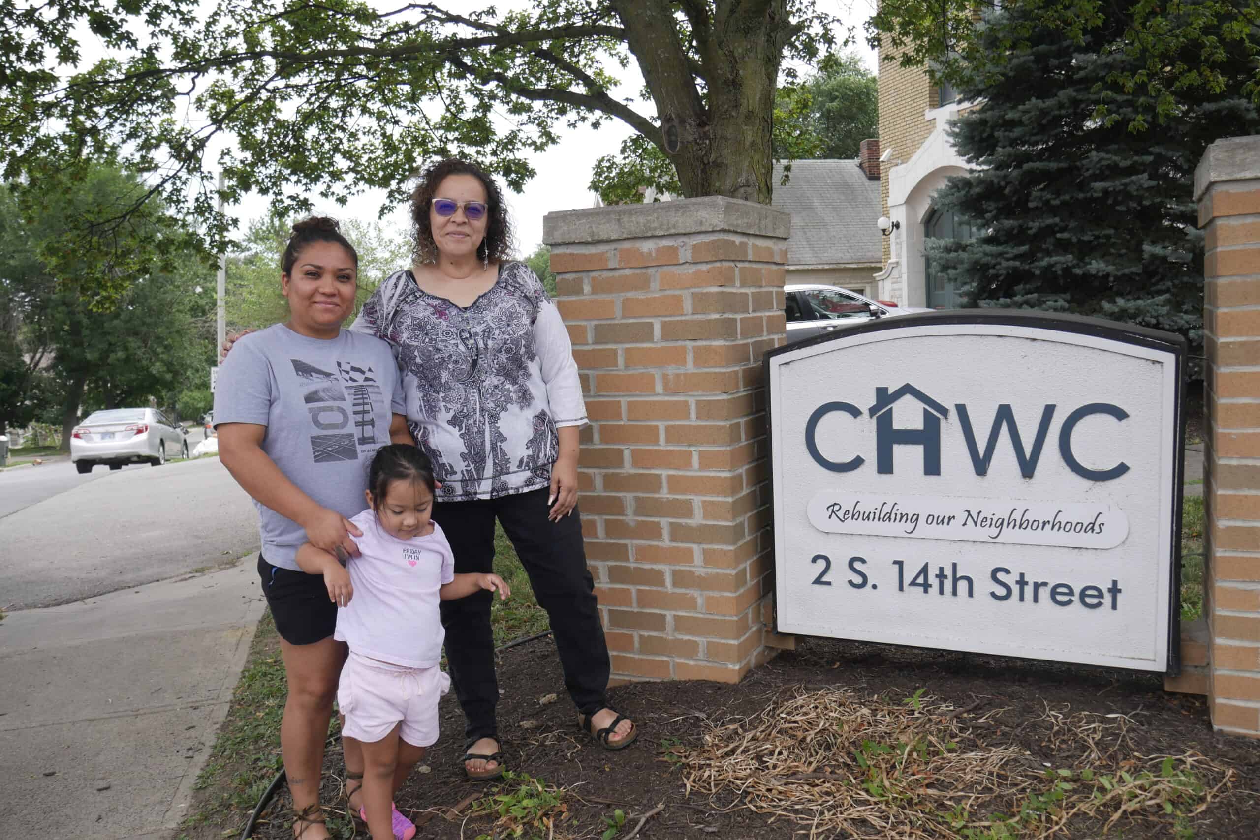 Rita and her daughter stand with Gloria, the CHWC housing counselor who's worked with them, outside of CHWC's office. 