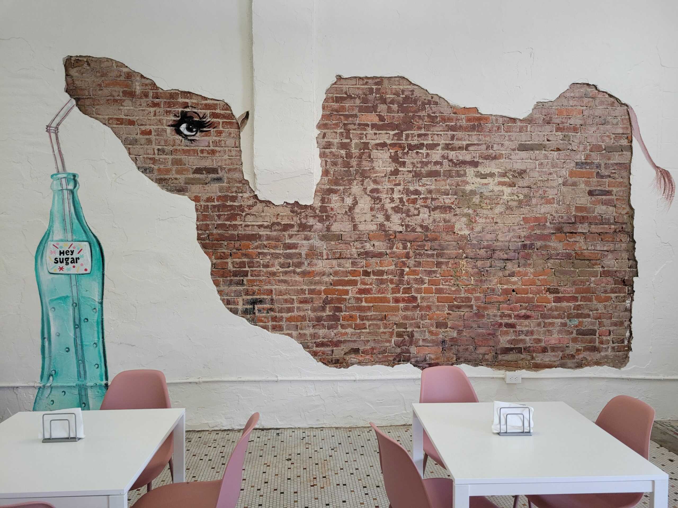 A camel made out of exposed brick and paint on the wall of Hey Sugar.